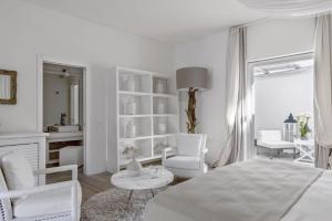 a white room with a bed and chairs and a table at Relais Corte Degli Aragonesi in Ischia +37 photos