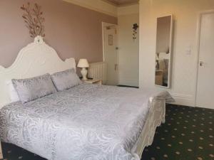 a bedroom with a white bed with a white comforter at Athol Park Guest House in Port Erin
