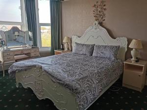 a bedroom with a large bed and a mirror at Athol Park Guest House in Port Erin