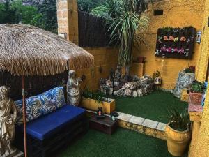 patio z niebieską kanapą i słomianym parasolem w obiekcie Lantica roccia w mieście Manzanares el Real