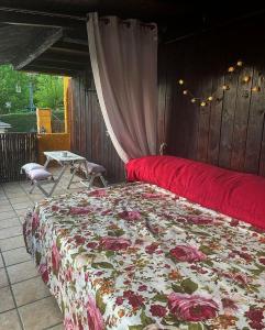 1 dormitorio con cama roja y manta floral en Lantica roccia en Manzanares el Real