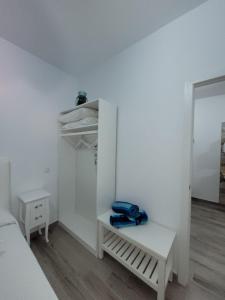 a white bedroom with a bed and a blue bag on a bench at Heva Home in Tarajalejo