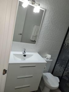 ein Badezimmer mit Waschbecken, Toilette und Spiegel in der Unterkunft Heva Home in Tarajalejo