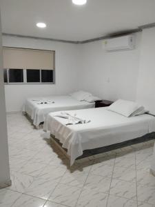 two beds in a room with white walls at Hotel Kariary in Puerto Boyacá