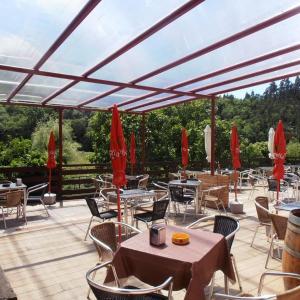 a patio with tables and chairs and red umbrellas at hotel el candano in Pravia