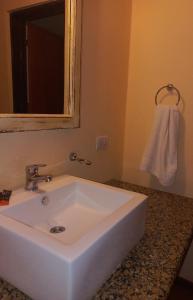 y baño con lavabo blanco y espejo. en Posada Faro Serrano en Villa General Belgrano
