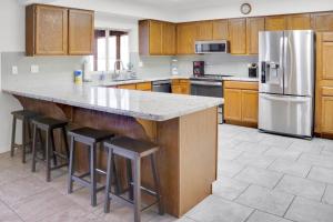 a kitchen with wooden cabinets and a large island with bar stools at *NEW* COZY POOL HOME - HEART OF LAKE HAVASU in Lake Havasu City