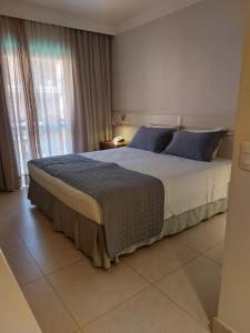 a bedroom with a large bed with blue pillows at Hotel Jurerê Beach Village - Apto pé na areia in Florianópolis
