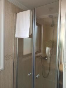 una doccia con porta in vetro e asciugamano bianco di A casiña de Estela a Caldas de Reis