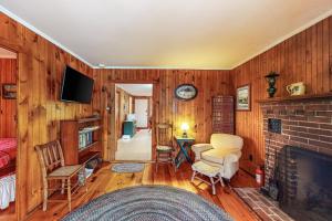 a living room with wood paneling and a fireplace at Boulder Pointe Cottage in Raymond