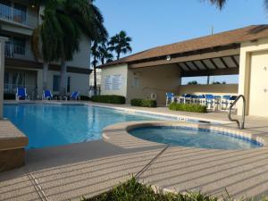 a swimming pool in front of a hotel with blue chairs at Fishermans Landing on The Bay- Las Marinas in South Padre Island