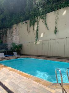 uma grande piscina azul com duas cadeiras ao lado em Suite Real Residencial no Rio de Janeiro