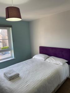 um quarto com uma cama branca e uma cabeceira roxa em Newbuild - 3 bedrooms, 2 baths,5 mins from airport em Edimburgo