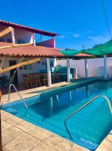 a swimming pool with green umbrellas and a house at Bella casa frente al mar, con piscina privada. in Atitancito