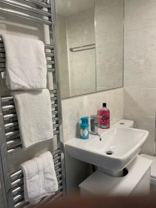 a bathroom with a sink and a mirror and towels at Newbuild - 3 bedrooms, 2 baths,5 mins from airport in Edinburgh