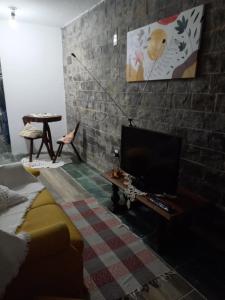 a living room with a tv on a brick wall at Apartamento para casal em São Lourenço in São Lourenço