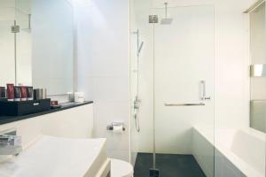 a bathroom with a toilet and a glass shower at Quincy Hotel Singapore by Far East Hospitality in Singapore