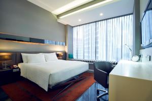 a hotel room with a bed and a desk with a chair at Quincy Hotel Singapore by Far East Hospitality in Singapore