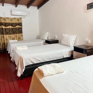 Zimmer mit 3 Betten und weißer Bettwäsche in der Unterkunft Adhara Apart in Puerto Iguazú
