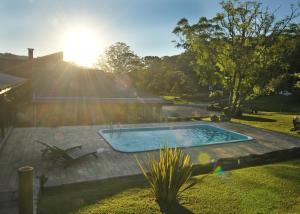 a swimming pool in a yard with the sun setting at A Estalagem hospedaria in Flores da Cunha