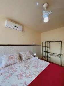 a bedroom with a bed with a red blanket and a fan at Pousada da Villa in Lençóis