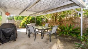 un patio con mesa y sillas bajo una pérgola en Dog Lovers Retreat, en Beachmere