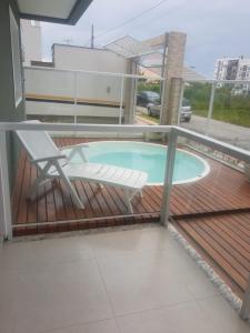 a deck with a chair and a swimming pool at DEUS é bom o tempo todo in Governador Celso Ramos