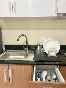 a kitchen counter with a sink and a plate and utensils at Luxury Hotel Type Condo Near NAIA Manila Airport in Manila