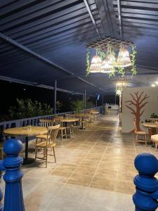 a covered patio with tables and chairs and a chandelier at URQU Glamping cerca a Bogota in Silvania