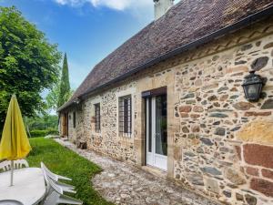 a stone cottage with a patio and an umbrella at Lively holiday home with private pool in Sainte-Trie