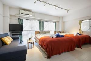 a bedroom with two beds and a tv and a couch at G&R House 102 in Tokyo