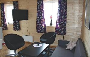 SkipnesにあるCozy Apartment In Sandstad With Wifiの椅子2脚、テーブル、テレビが備わる客室です。