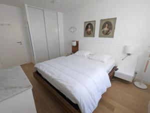 a bedroom with a white bed and two pictures on the wall at Appartement Arcachon, 2 pièces, 2 personnes - FR-1-420-90 in Arcachon