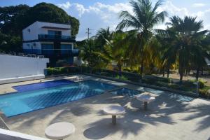 a swimming pool with two stools and a building at Cabaña en coveñas en acogedor conjunto residencial in Coveñas