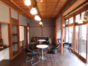 Habitación con mesas, sillas y ventanas. en Guesthouse Neruyama, en Nagato