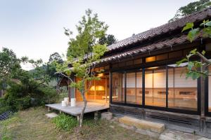 un árbol se sienta en un banco frente a una casa en 日貫一日　安田邸, en Ohnan-cho