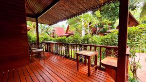 a wooden deck with benches and a table on it at Longtail Beach Resort in Thong Nai Pan Yai