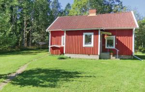 Uma casa vermelha com um jardim relvado à frente. em 2 Bedroom Awesome Home In Hgsby em Hultsnäs