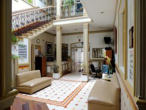 una sala de estar con sofás y una escalera. en Hotel La Orquidea, en Cuenca
