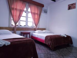 two beds in a room with a window at Hotel Crossman in Puerto Ayora