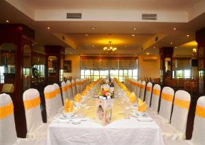 una mesa larga con sillas blancas y naranjas en una habitación en Central Hotel, en Quảng Ngãi