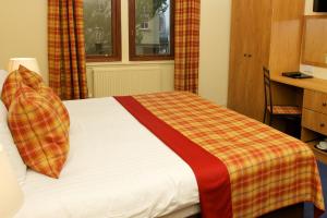 a bedroom with a bed with a plaid blanket at The Pipers' Tryst Hotel in Glasgow