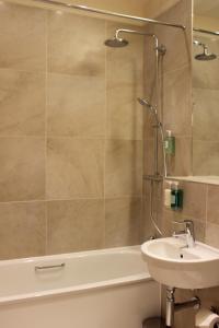 uma casa de banho com um lavatório, uma banheira e um chuveiro em The Pipers' Tryst Hotel em Glasgow