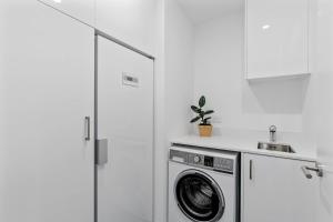 a kitchen with a washing machine in a white kitchen at Luxurious Lakefront Penthouse in Wanaka