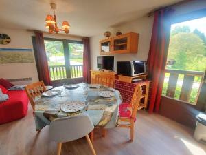 a dining room with a table with chairs and a television at Cosy appartement au centre de Morillon, proche télécabine, balcon et parking - FR-1-624-104 in Morillon