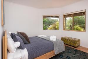 a bedroom with a large bed with two windows at Gypsy Rise in Dunsborough