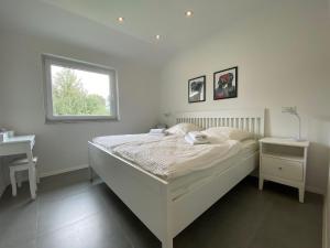 ein weißes Schlafzimmer mit einem Bett und einem Fenster in der Unterkunft FriesenHuus Ferienhaus Sehestedt in Sehestedt