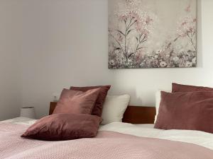 una camera da letto con un letto con cuscini marroni e un dipinto di Kuh Blick Ferienhaus Sehestedt a Sehestedt