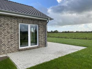 a brick building with a window next to a field at Kuh Blick Ferienhaus Sehestedt in Sehestedt
