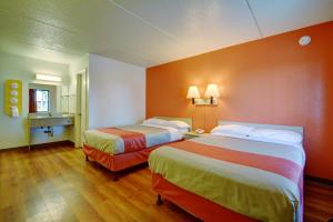 two beds in a hotel room with orange walls at Motel 6-Chicopee, MA - Springfield in Chicopee